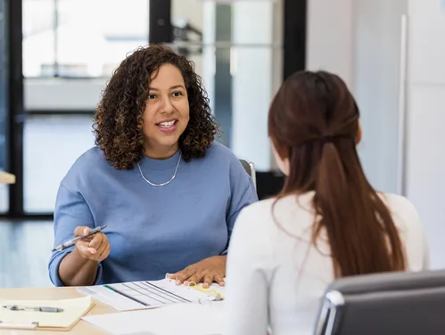 A woman speaks with another woman about assessing their job skills. 