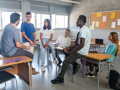 Six students of various ethnicities gather in a classroom. 