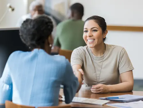 A woman veteran shakes hands with an employer.