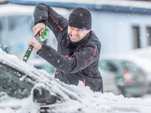 Angry guy cleaning ice off windshield