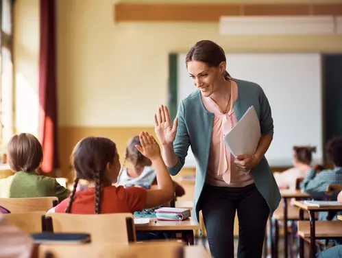 teacher high-fives student in classroom