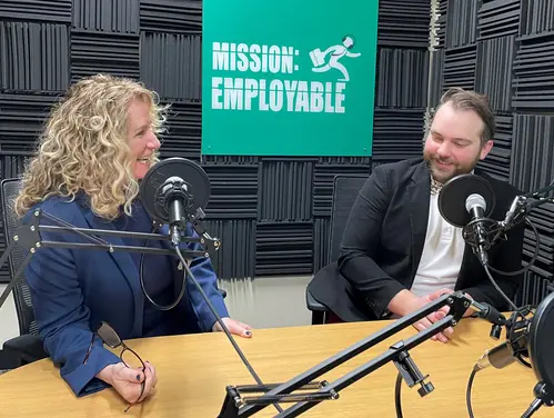 Kathy Leggett and Ben Oldach smile from behind podcast microphones.