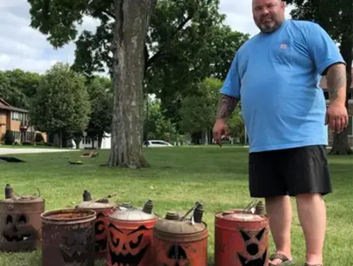 Brad Thill stands next to jack-o-lanterns made from gas cans.