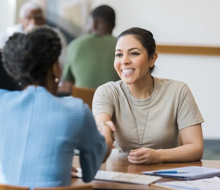 A woman veteran shakes hands with an employer.