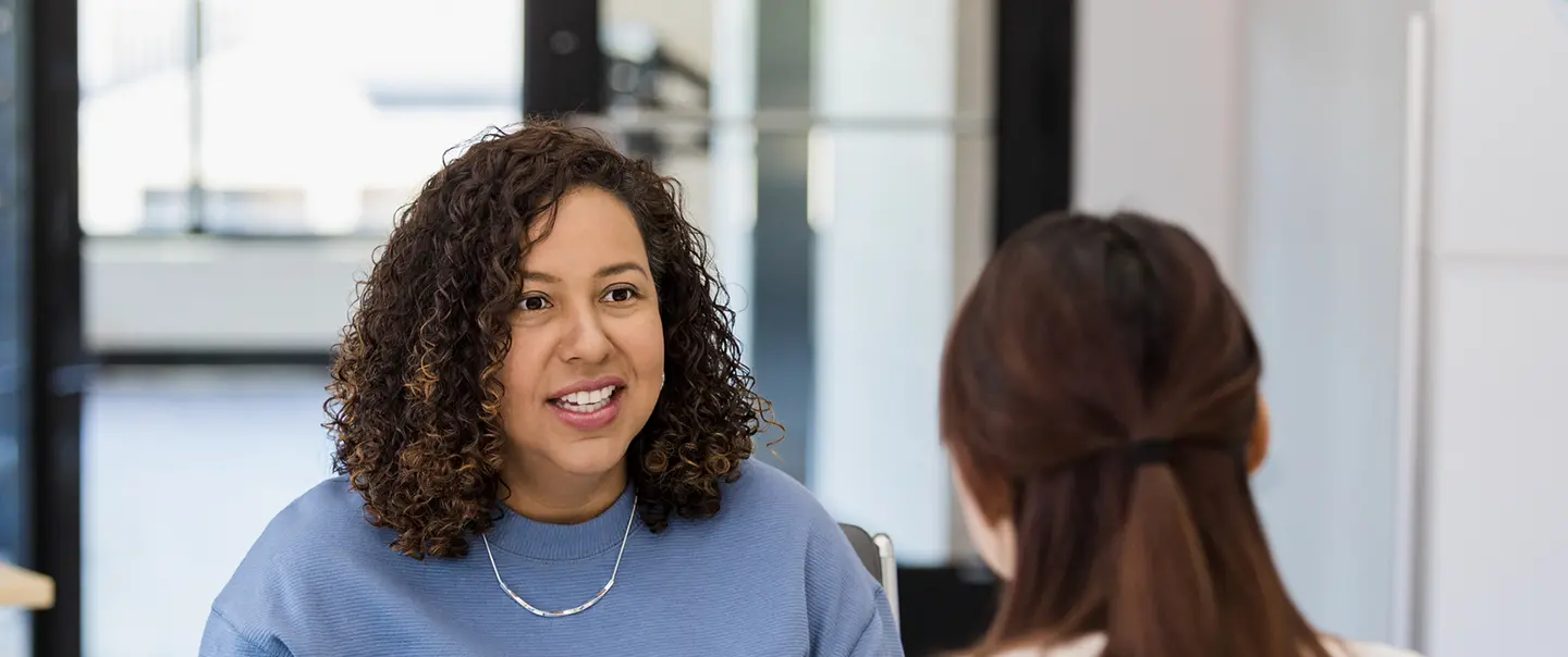 A woman speaks with another woman about assessing their job skills. 