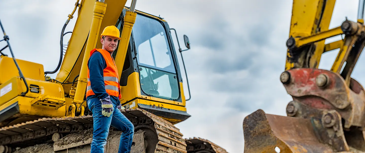 A construction worker stands next to a bulldozer.