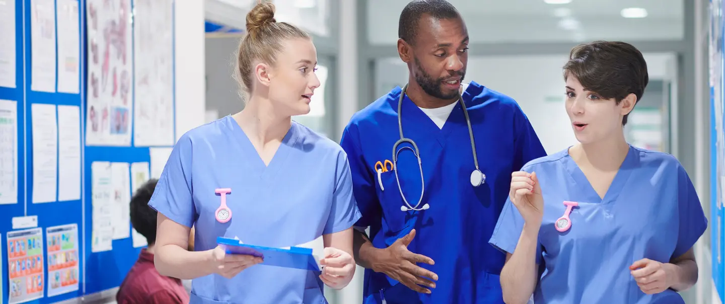 Photo of a Nurse Walking and Talking with a Doctor in a Health Care Setting.