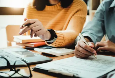 Photo of two people sitting down with paperwork and applying for something.