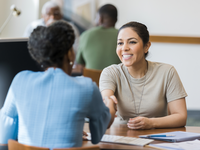 A female veteran shakes hands with an employer.