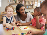 Photo of  Woman sitting next to a table and who is providing child care.