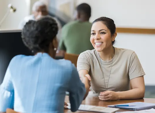 A female veteran shakes hands with an employer.