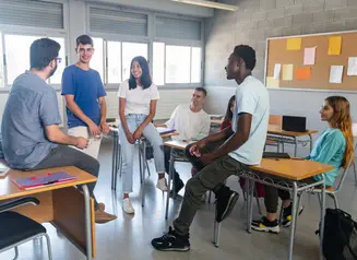 Six students of various ethnicities gather in a classroom. 