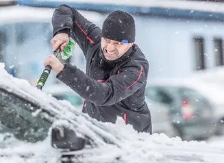 Angry guy cleaning ice off windshield