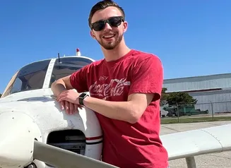 Anthony Reyman leaning on an airplane.