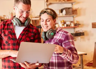 two smiling people looking at construction plans