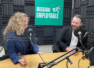 Kathy Leggett and Ben Oldach smile from behind podcast microphones.