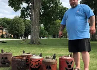 Brad Thill stands next to jack-o-lanterns made from gas cans.