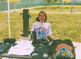 Kevin Ha behind a table displaying his product offering.