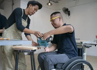 business manager helping new employee in wheelchair learn the job