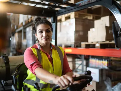 Woman on a forklift in a warehouse.