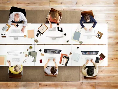 Overhead view of six people working at a large table. 