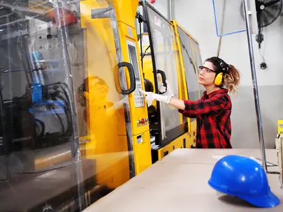 Woman operates a machine at an advanced manufacturing plant.